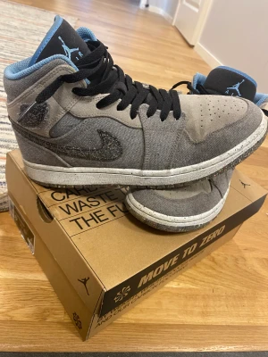 Air Jordan 1 Mid - Säljer ett par Air Jordan 1 mids i färgen gray fog university blue-black. Skorna är i gott skick och lite använda. Storlek 42 men passar även 41. Säljes då jag växt ur dem. Kostar ca 2000 SEK på stockx. Hör av er om ni önskar fler bilder!