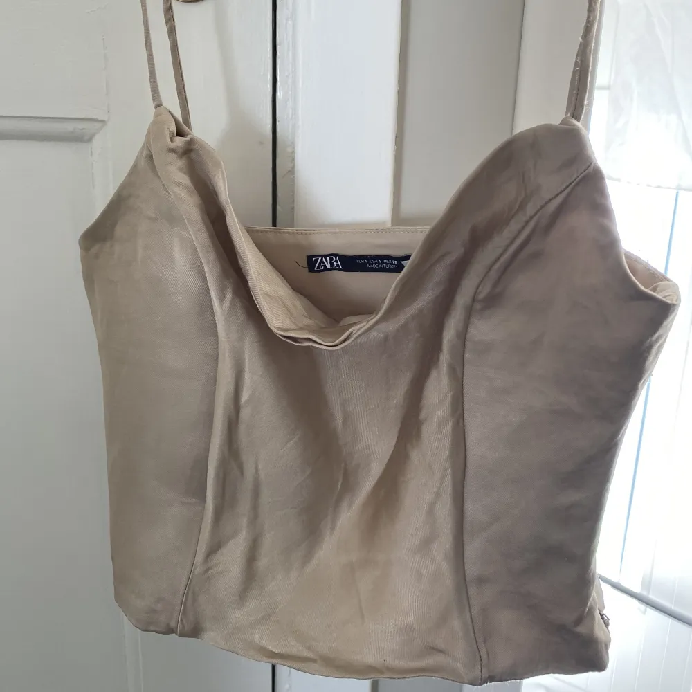 En metallguldig corsettopp från Zara. Köpt för 1,5 år sedan, endast använd en gång. Säljer pågrund av att den har blivit för liten. Skulle passa någon som är mindre i bysten än mig. Perfekt till ett par Jeans eller kostymbyxor. (Dragkedja vid sidan). Toppar.