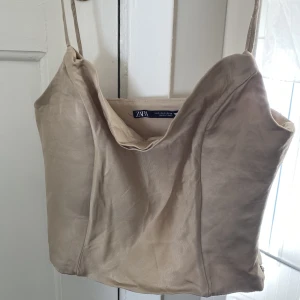 Fest topp från Zara - En metallguldig corsettopp från Zara. Köpt för 1,5 år sedan, endast använd en gång. Säljer pågrund av att den har blivit för liten. Skulle passa någon som är mindre i bysten än mig. Perfekt till ett par Jeans eller kostymbyxor. (Dragkedja vid sidan)