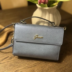 Guess crossbody - Säljer min Guess väska, använt 1 gång. Mycket fint skick. Mer ljusblå i verkligheten, sista bilden är mest rättvis köpt för 1599kr 