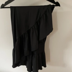 Maxikjol - Långkjol, omlott med volanger, svart, knappar i midjan. Sparsamt använd. 