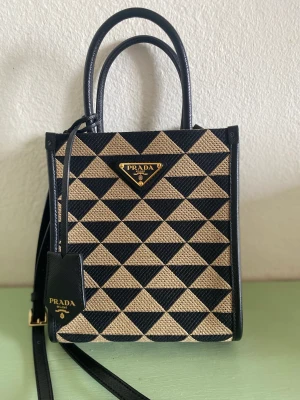 Prada  Symbole Bag - Hej jag säljer min Prada väska i nyskick. Färgen och storleken är svår att få tag på. Kvitto finns!  Modell: Prada Symbole embroidered fabric mini bag Storlek: Height: 19cm, Length: 6cm, Width: 17cm Nypris: 22 100kr