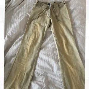 Jeans  - Beiga jeans med snörning upptill. Byxorna är midwaist/lowwaist i storlek 12 enligt lapp men passar som storlek 36 
