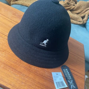 Kangol bucket hat wool - Helt ny oanvänd Kangol bucket hat i ull. Storlek är tyvärr lite oklart då jag köpte den som storlek L på capstore.se men tyvärr var storlekslappen avklippt när jag fick den, passar ett lite mindre huvud.  Nypris på dessa ligger på runt 500-800kr