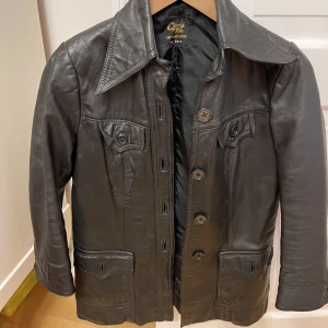 Svart skinnjacka🕺🏽🪩 - Svart skinnjacka med knappar och lite kortare ärm. Köpt secondhand för 800 kr. Använd en gång av mig. I fint skick! Står ingen storlek i men skulle gissa på Small. Kan mötas i Göteborg eller skicka, köparen står för frakt.