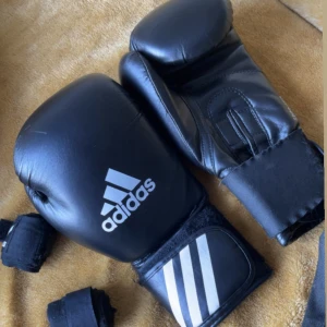 Boxhandskar  - Säljer mina Adidas Boxhandskar nu har köpt nya. De är använda 3 veckor och har inga skador på elle inne. Bandage är Outshock och är 3,6 meter. 