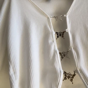 Vit topp med silver fjärilar - Köpt i Miami , använt endast en gång . Det går även att ta bort fjärilarna. Inte genomskinlig alls.