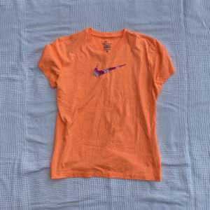 Orange tränings T-shirt från Nike med rosa logga! Jättesnygg och bra skick bara smått nopprig men syns knappt! Den är L i barnstorlek men funkar som en S för vuxna också. Jag har S och kan ha den utan problem.