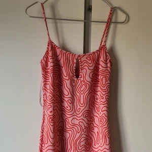 Mönstrad oanvänd långklänning från zara - Rosa med rött mönster, samt utskuret mönster i rygg och liten slits nedtill i bak. Figurnära lång modell