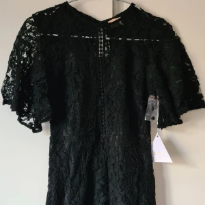 Oanvänd kort svart klänning i sprts från love triangle - Lappar kvar, kort tajt modell, öppet i ryggen.