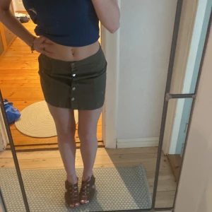 Grön kjol  - Superfin kort, militär-grön kjol från HM med knappar (nyskick) i storlek 34. Pris kan diskuteras. Köparen står för frakt! 