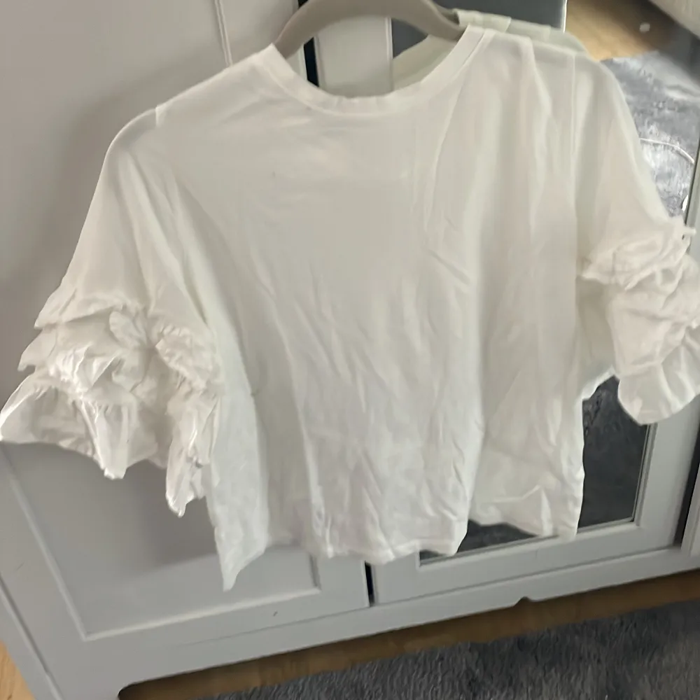 Säljer denna vita t-shirt med volanger på ärmarna ifrån hm,storlek S💓. T-shirts.