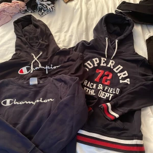 Paket av hoodies - Fint paket av hoodies och sweatshirt. Champion och superdry, Champion i sweatshirt har minimala defekter som kan visas på ytterligare bilder på texten. De andra är använda men bra skick. Hör av er vid ytterligare frågor🫶