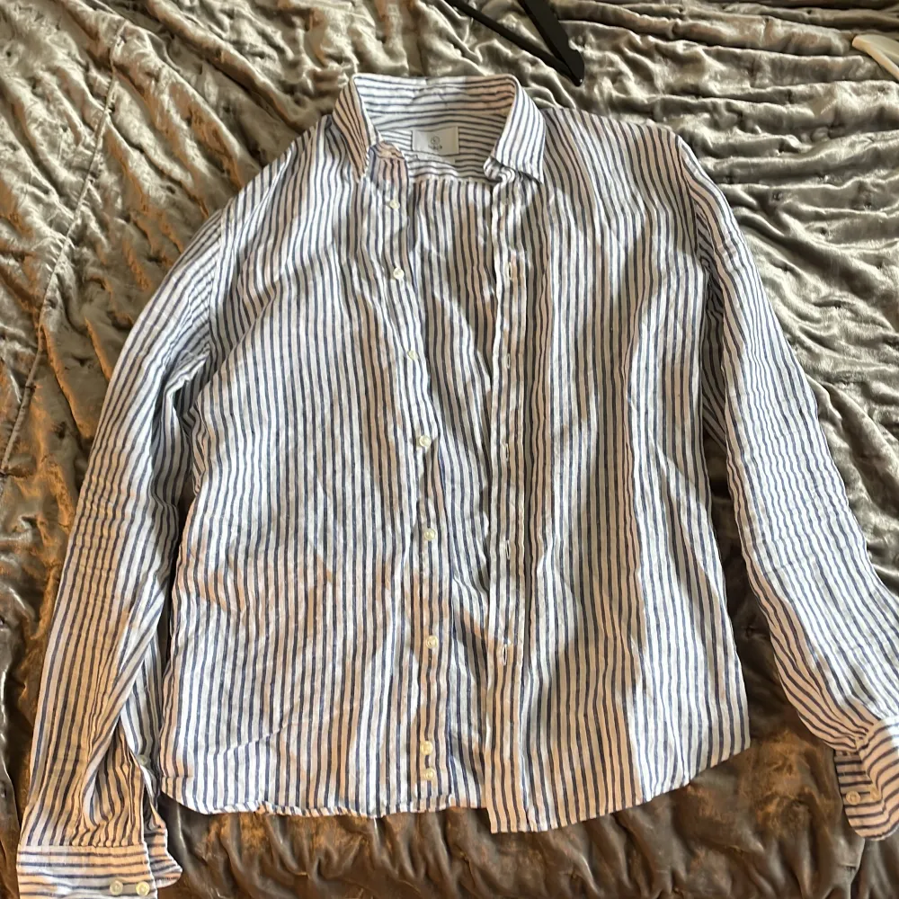 Hej! Säljer lite plagg från sommaren, här är en vit blå randig linneskjorta från märket bläck i fin kvalitet. Har ni några frågor är det bara att höra av sig.  Den är storlek S men passar M med . Skjortor.
