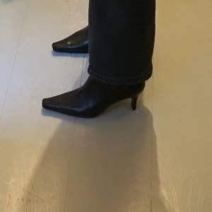 Modell: stövlett /boots med dragkedja  Material: skinn; sula: gummi Klackhöjd: 6,5 cm, omkrets uppe i skaftet ca 27 cm Storlek: 38 Färg: Svart  Använda 1-2 ggr