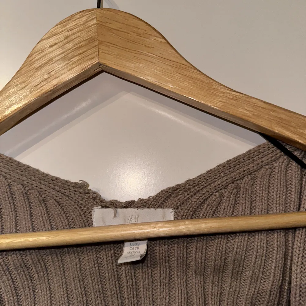 En kortare cardigan med långa armar, stickad material i beige färg, den har sytts upp ytters långt upp men inget som påverkar plagget. . Tröjor & Koftor.