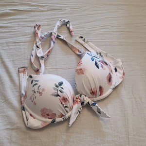Bikiniöverdel - En vit blommig bikiniöverdel. Endast använd fåtal gånger i poolvatten och inte i havsvatten. Finns en knytning framtill som detalj. Har push-up. 