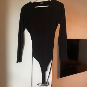 Svart body med öppen rygg - Svart body med öppen rygg & knyte.  Använd få gånger.  Från GinaTricot 