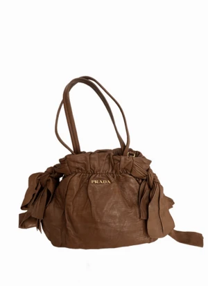 Prada Bow Nappa Leather Väska (Vintage) - **äkthetsgaranti, kontakta mig för info** Möjlighet att hämta i Stockholm!  En elegant och feminin Prada-väska. Vintage och unik.  Axelrem medföljer.  Fler foton, info samt andra vintageväskor ur min kollektion —> pretti.se
