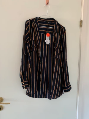 Randig skjorta - Randig skjorta i färgerna marinblå och orange. Från Vero Moda.