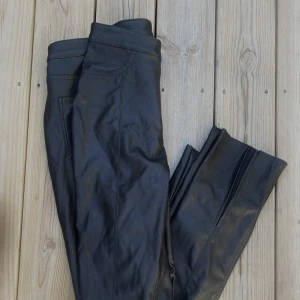 Svarta ”skinn”brallor med slits!  - Skitsnygha brallor med slits nedtill. Kvalitén på bilden är skitdålig. Byxorna är hela och superfina! Från H&M storlek 38🌺