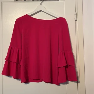Cerise blus med volangärm - Cerise bluse med volangärm och v-ringad rygg med knyte