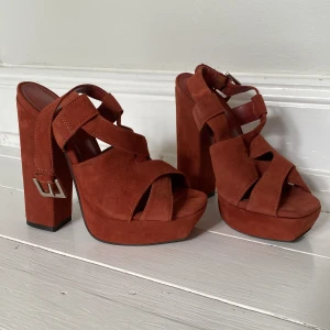 Helt nya klackar - Storlek 36 Mocka  Röd/bruna  Aldrig använda Märke: Carvela  14cm klack  Svårt att säga färg. Typ koppar/röd/orange 