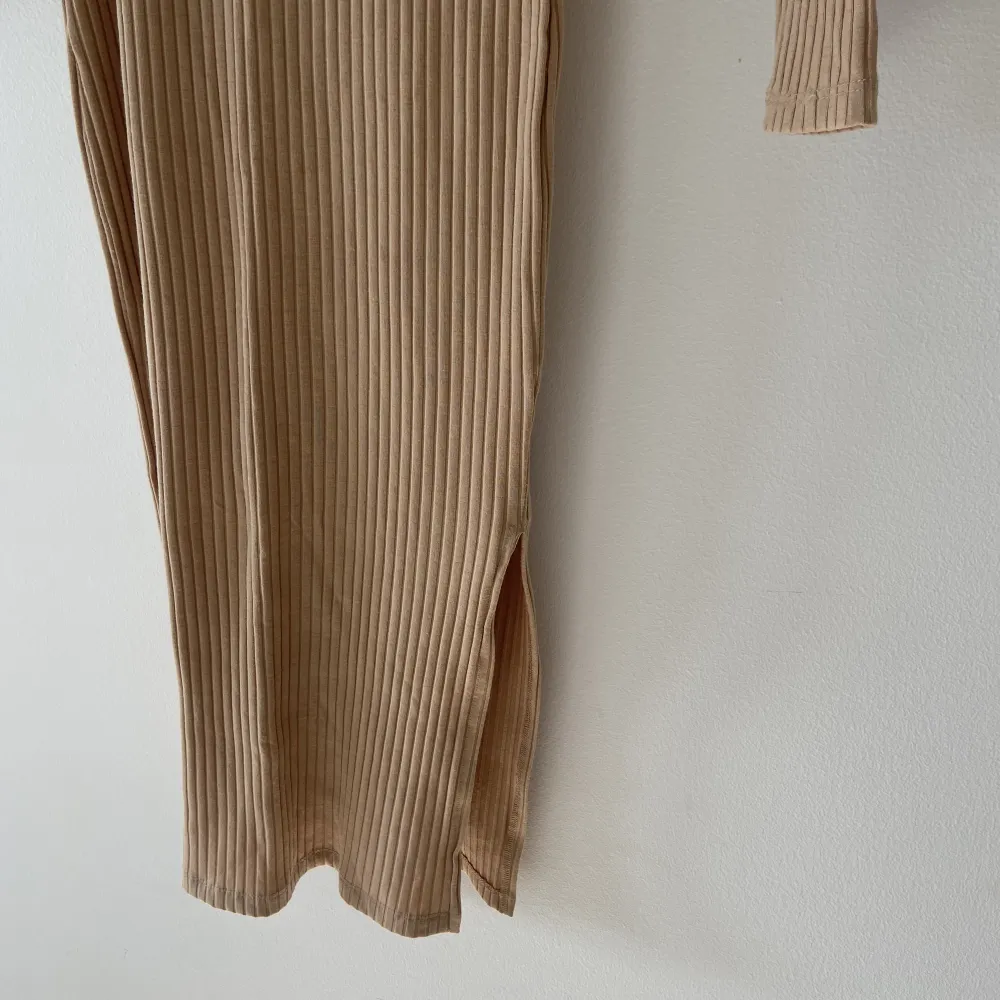 Långärmad ribbad klänning. Beige i storlek XS. Ganska lång, går en liten bit under knäna på mig som är ungefär 165 cm lång. Slits på vänster sida. Den är använd 2-3 gånger max.  Köpt på Nelly. . Klänningar.