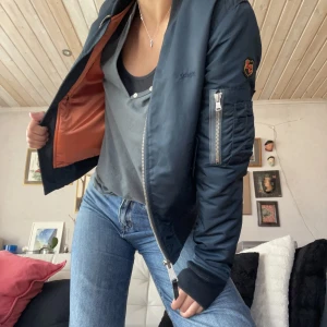 Vintage Bomberjacka - Marinblå vintage bomberjacka från USA säljes då den blivit för liten för mig. Jackan är i gott skick trots att den är välanvänd pga dess goda kvalité.   Storlek S men känns mer som en XS. 