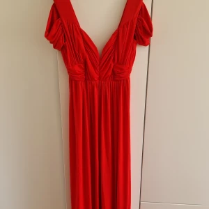 Röd långklänning - Röd långklänning med slits. Från ASOS, storlek 38/S-M. Aldrig använd! Fint material som ej blir skrynkligt.