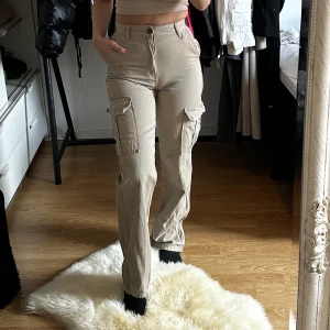 Cargo byxor  - Säljer mina fina cargo byxor i en superfin färg som nästan inte går att förklara. Ljusbruna/beiga/mörkgröna. Sitter skit snyggt på! Köpta på stradivarius 