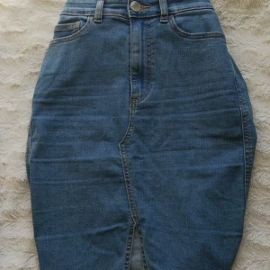 Jeanskjol med slits - Halvlång jeanskjol med slits. Slutar runt knähöjd. Hög i midjan. Aldrig använd. Storlek small/36