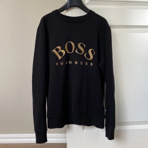 HUGO BOSS tröja⚡️ - Säljer denna svarta snygga herr Hugo Boss tröjan med guld broderad text. Den är i väldigt fint skick!⚡️ QR kod finns på siste bilden som visar att den är äkta!