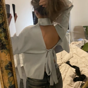 blå polotröja - ljusblå polotröja med öppen rygg och knytning, går att knyta både där fram och bak beroende på vad man tycker är finast. superfint skick! 