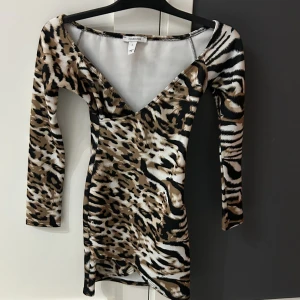 Klänning  - Klänning köpte från Nelly (Oneness) använd bara en gång vid en fest, stretchig material normal i storlek och är i mycket bra skick. Fin djurmönster i svart, beige och ljusbrun färger. 