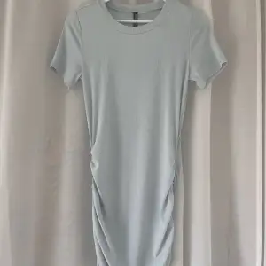 En jättefin draperad ljusblå klänning som är helt oanvänd. Jag har bara testad den på. Det går att välja längd på klänningen då man väljer hur mycket man vill dra åt snörena. Säljs då den inte kommit till användning! 💕