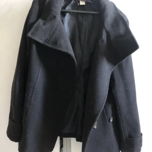 Kort kappa - Säljer min svarta korta kappa då jag köpt en ny, den är köpt second hand och är i stolek M (blir lite oversize om man har stolek S) kan självklart skicka bilder med plagget på om det önskas 💕