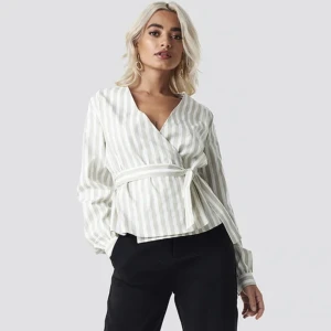 Randig skjorta NA-KD - Randig skjorta som man knyter, färgen är vit och beige/grå.  Inköpt på NA-KD, på hemsidan heter den ”Wrap Over Striped Blouse”. Nypris 349 kr.  Toppen skick. Skriv för fler bilder!💓