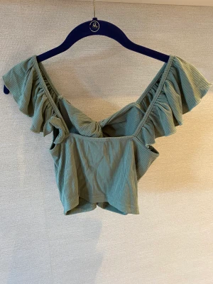 Linne  - Grönt linne med volang midjemått på 33 cm och längd på 17cm. Inte använd, bra skick 