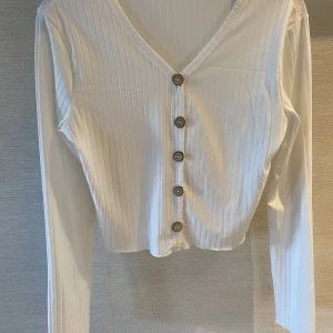 Tröja  - långärmad vit tröja med decor knappar. Innearm längd är 50 cm och midjemått 74cm, storlek S 