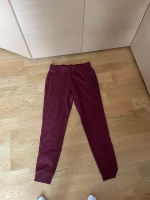 EA7 byxor - EA7 vinröda mjukisbyxor som är en del av en dress.  Jättebekväma och fina. De är i storlek S  Koftan finns även om man är intresserad