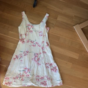 Silkesklänning Tommy Bahama - Klänning i 100% silke. Storlek okänd men gissar på en medium. Ljusgul med rosa blommor och gröna blad. Dragkedja vänster sida.