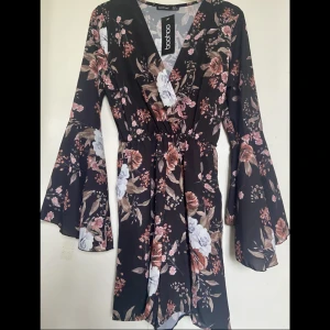 Playsuit - Från Boohoo Namn: Floral flared sleeve tie waist playsuit Färg: svart med blommönster Nypris: 280kr Säljer för att jag köpte två olika storlekar, aldrig använd
