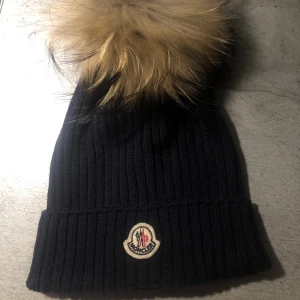 Monclear mössa - Monclear mössa , ungdomsstorlek men passar både vuxna och barn. Har inget äkthetsbevis eller kvittot tyvärr men köpt på NK i Stockholm förra året :)  Möts upp i Sthlm :) 