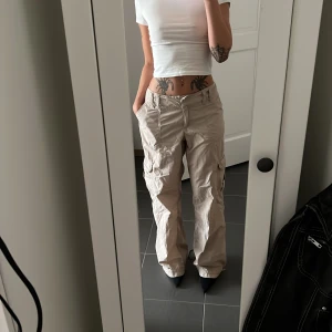 Cargo byxor beige - Beiga cargo byxor från hm, storlek 38 men funkar bra som lågmidjade för en 34/36axs/S, sitter fast ett beige skärp som kommer med byxorna, som jag brukar knyta i bak vilket även gör storleken och passformen väldigt justerbar! 