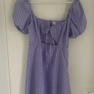 lila sommarklänning - En jättefin rutig lila klänning med ett ”hål” i mitten. Använd några få gånger. 