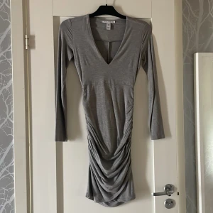 Fodralklänning - T-shirt tyg med v-ringning och drappering runt höfterna så man själv kan justera längd/drappering.