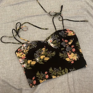 Floral crop top with adjustable straps - Very beautiful piece fit for the summer. Size is L - fit for M. You can tie both side to the desired length, the length of the strings on each side are pretty long.