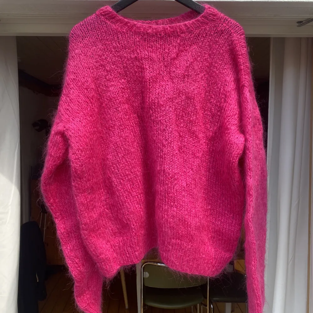 En tjock stickad tröja i vad jag tror är en Ull blandning eller liknande. Jättefin djup och intensiv rosa. Den är hemmastickad och skulle uppskatta den som en S-M. Fint skick. Lite små-skrynklig endast då den legat i garderoben ☺️. Stickat.