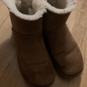 Uggs - Säljer mina uggs i modellen mini bailey bow II boot.  Säljer då de är för stora på mig och gillar ej modellen så mycket. Köpta för 2800kr säljer för 1500kr, storlek 41. Bilder och mer info🥰